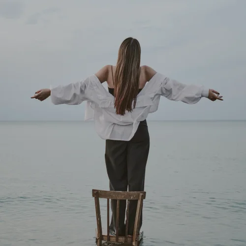 Donna a braccia aperte davanti al mare, simbolo di libertà e benessere